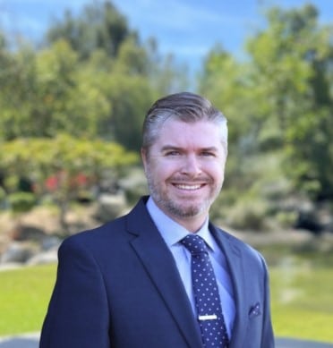 Ben Baldwin, Business Development team member at American Golf, smiling outdoors in professional attire on a golf course