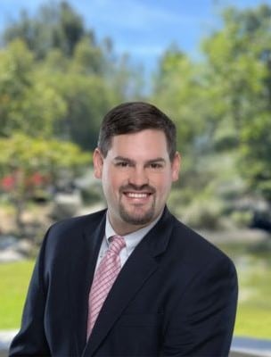 Thomas Fowler, Business Development team member at American Golf, smiling outdoors in professional attire on a golf course